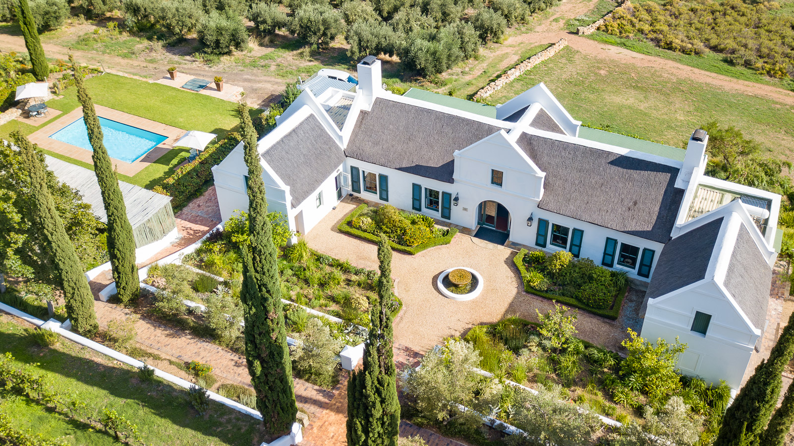 Aerial view of Galenia Estate — the Cape Dutch manor house, pool and gardens surrounded by olive groves